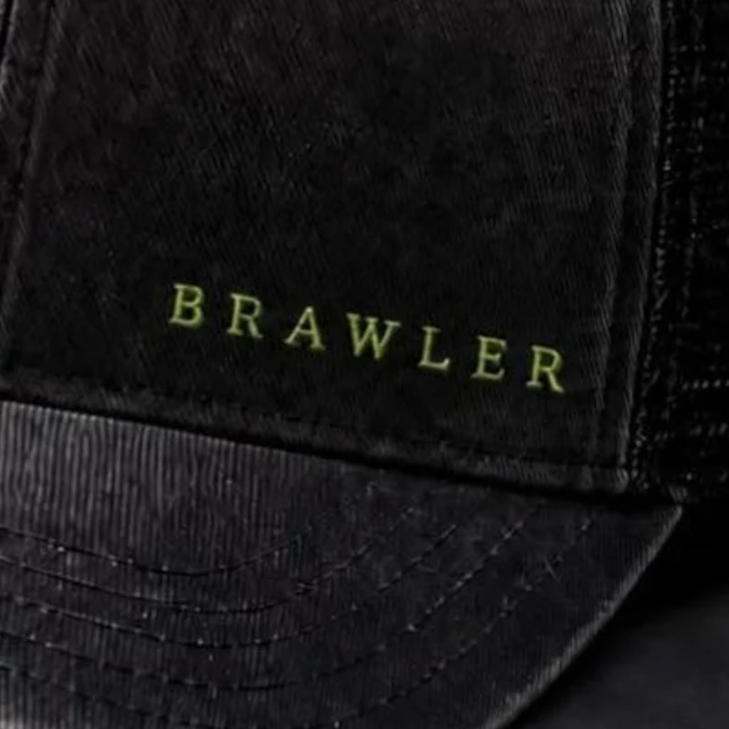 Close-up of lime BRAWLER embroidery stitched into washed black cotton